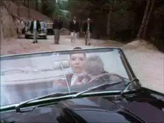 Mrs. Peel see the henchmen bearing down on her car in the rear-view mirror