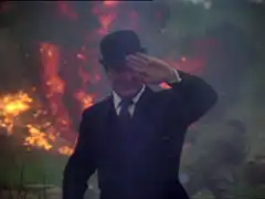 Steed sheilds his face from the heat and smoke as he walks through a burning assault course