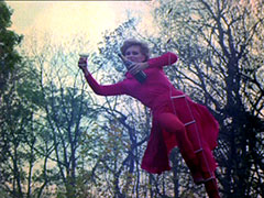 Purdey is rescued from the minefield - she hangs from a ladder under a helicopter, holding a bottle of champagne and a glass