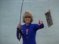Purdey smiles broadly as she holds up the circuit board hooked to the end of her fishing line