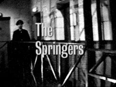 title card: The Springers superimposed on a guard patrolling outside some prison cells