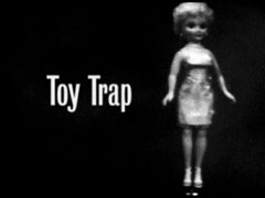 title card: toy Trap superimposed on dark background with a doll alongside