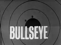 title card: white all caps text reading ‘Bullseye’ superimposed on a shooting target with two holes near the bullseye