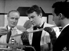 Sub-Lt Graham conducts an experiment in the lab, flanked by Dr. Thorne and another scientist