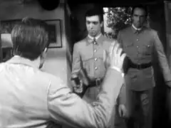 Two embassy guards burst into the house where Mark is hiding, causing him to raise his hands in surrender