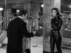 Mrs. Peel approaches Massey who points a gun at her. Undaunted, she holds out her left hand to take his pistol