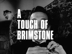 title card: white all caps text reading ‘A TOUCH OF BRIMSTONE’ outlined in black and superimposed on Cartney sitting in his armchair eating chocolates
