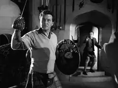 Steed, sword and targe in hand, turns to face Angus as Roberton appears in the door behind him and takes aim with his revolver