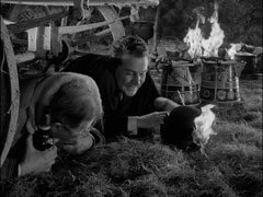 Carlyon and Steed take cover under the wagon as the flaming arrows rain in; Steed is trying to extinguish the arrow that has skewered his bowler hat