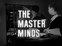 title card: white all caps text reading ‘THE MASTER MINDS’ outlined in black and superimposed on the scene in the vault of the guardsmen looting the safe