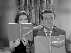 Steed and Emma read books on ventriloquism ( ‘ADVANCED VENTRILOQUISM’ and ‘THE VENTRILOQUISTS’) inside a moving caravan