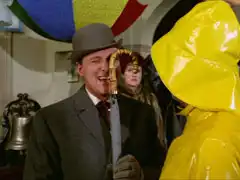 Steed holds his umbrella up to his face and peers thruogh the handle at Winters, telling him the handle is loose. Olga looks on, baffled, in the background