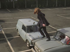 Mrs. Peel leaps onto a car to avoid being struck down by Gordon, then turns to try to wrestle him from his vehicle