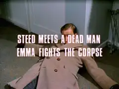 subtitle card: white all caps text with black dropshadow to the left reading ‘STEED MEETS A DEAD MAN
			EMMA FIGHTS THE CORPSE’ superimposed on Whittle, who has fainted and fallen against the wall