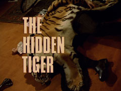 title card: white all caps text with black dropshadow to the left reading ‘THE HIDDEN TIGER’ superimposed on a tiger skin lying over Williams’ contorted body