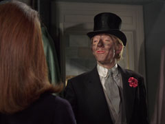 Upper class chimney sweep Bert Smith smiles inanely at Mrs. Peel, whose back is to us. His face, top hat and morning suit are covered in soot and grime