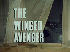 title card: white all caps text with black dropshadow to the left reading ‘THE WINGED AVENGER’ superimposed on a thin white curtain blowing in the wind coming through the large broken window behind it