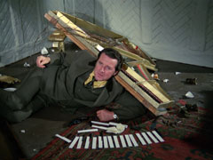 Steed lies on the floor, covered in the remains of the piano as the outer woodwork has been destroyed