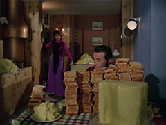 Tara stands in the background, surprised to find Steed trying to use up the left-over butter om a mountain of toast