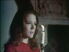 Mrs Peel cautiously explores the castle while holding a lit candle
