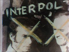 A black and white photograph of two men, their faces crossed out and the word INTERPOL written above them