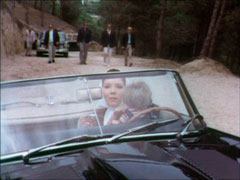 Mrs Peel see the henchmen bearing down on her car in the rear-view mirror