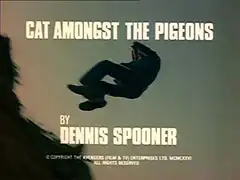 title card: white all caps text reading ‘CAT AMONGST THE PIGEONS BY DENNIS SPOONER’ superimposed on Merton falling backwards over a cliff