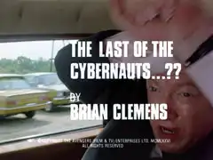 title card: white all caps text reading ‘The Last of the Cybernauts…?? BY BRIAN CLEMENS’ superimposed on Kane in his car, shielding his head from the inevitable crash with his hands