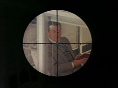 A view through Hara’s rifle scope of Steed, the crosshairs lined up on his necktie