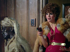 Purdey, in the guise of the fast talking streetwalker, Lolita, pulls out her pistol; she wears a hot pink dress and fur coat, and is chewing gum