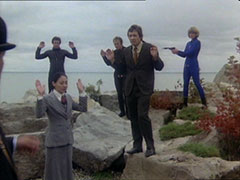 The Russian spies surrender on the lake shore, Purdey covering them with her pistol