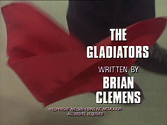 title card: white all caps text reading ‘THE
					GLADIATORS
					WRITTEN BY
					BRIAN
					CLEMENS’ superimposed on a close-up of Nada’s red handkerchief falling to the ground