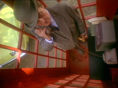 Top-down view of the interior of a telephone box in which Steed is on the phone