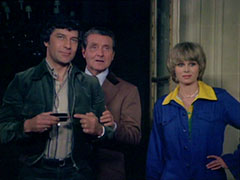 Gambit’s finger hovers over the detonator button, Steed and Purdey smiling at his side - Steed’s hand is on his elbow and is about to make him accidentally press the button