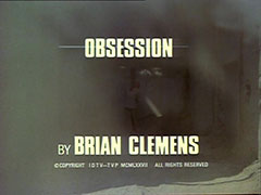title card: white all caps text reading ‘OBSESSION BY BRIAN CLEMENS’ superimposed on a dusty shot of Doomer tie to a stake at the end of a whitewahsed courtyard, having just been shot by a firing squad