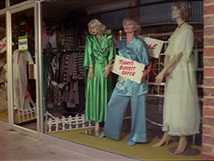 Purdey hides from the gang by posing in the shop window in her blue silk pyjamas, holding a white sign on which is printed, in red, ‘TODAY’S BIGGEST OFFER’