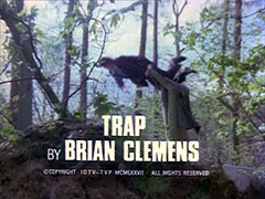 title card: white all caps text reading ‘TRAP BY BRIAN CLEMENS’ superimposed on Williams leaping over a barbed wire fence