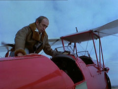 Turner climbs into a red biplane in order to escape