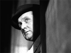 Publicity still: Steed peers from a doorway