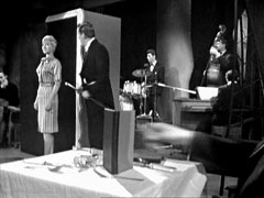 Venus anxiously prepares to enter the cabinet as Weston performs his act. The Dave Lee Trio can be seen in the background