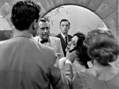 Steed hold a gun to Anna’s head, he and Cathy in the foreground, Anna between them. Rosas and Monroe behind him have no choice but to surrender