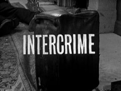 title card: white all caps text reading ‘INTERCRIME’ superimposed on a close-up of an up-turned case, the feet of a dead body in view behind it