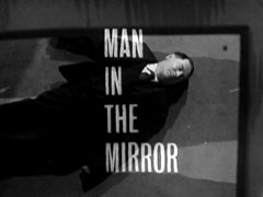 title card: white all caps text reading 'MAN IN THE MIRROR	' superimposed on a shot of the corspe, reflected in the mirror