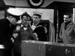Franks is apprehended by two sailors as Steed holds a gun on him