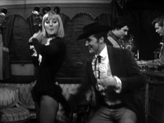 Steed cheekily tweaks the tail of Pussycat’s costume and she responds with saucily feigned indignation, Preston and the barman are in the background on the right