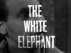 title card: white all caps text reading ‘THE WHITE ELEPHANT’ superimposed on an extreme close-up of George