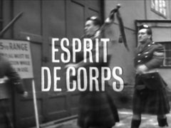 title card: white all caps text reading ‘ESPRIT DE CORPS’ superimposed with dark dropshadow over a shot of the kilted soldiers marching away after the execution, the piper in the middle of the frame