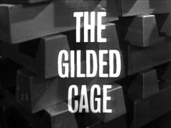 title card: white all caps text reading ‘THE GILDED CAGE’ superimposed on a neatly stacked pallet of gold ingots