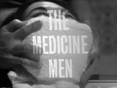 title card: white all caps text reading ‘THE MEDICINE MEN’ superimposed on Tu Hsiu Yung being smothered