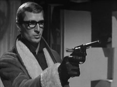 Medium shot showing Dyter pointing his revolver off-screen to where St John is standing